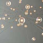 Low-angle view of light bulbs hanging from the ceiling, producing a drop-like effect.