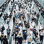 Crowd of busy commuters with protective face mask walking through platforms at subway station during office peak hours in the city