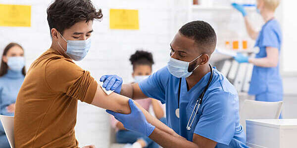 Young male patient receives coronavirus vaccines from a doctor.